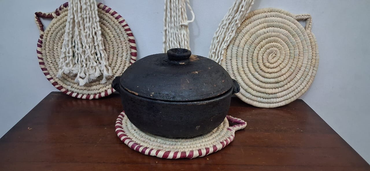 Black pot with a lid on woven coasters on a wooden surface